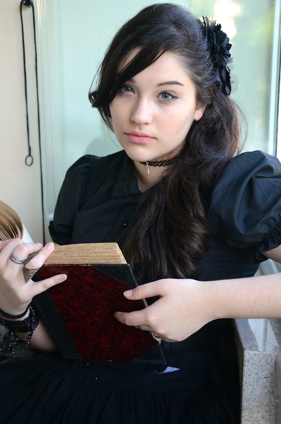woman holding book, black hair, reading, sitting