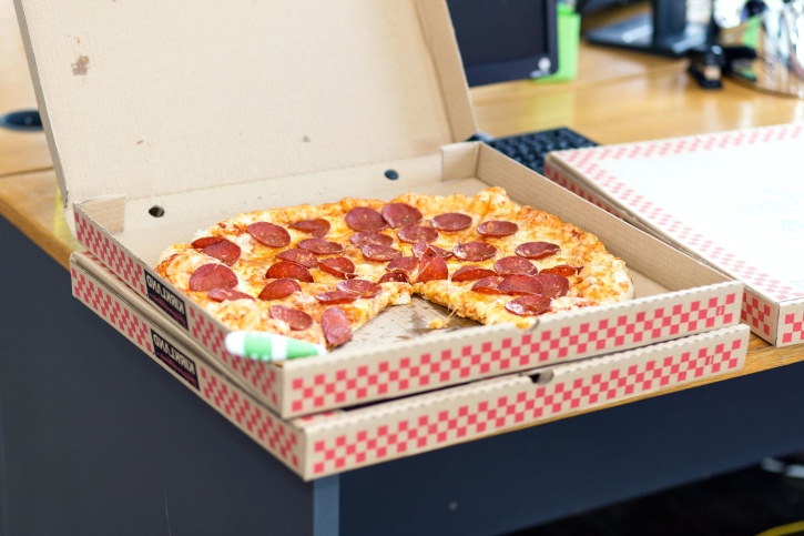 Open pizza box with three-quarters of a pepperoni pizza inside. 