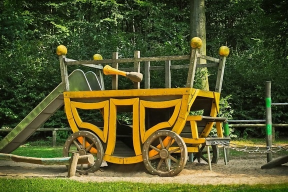 wooden carriage, tree, grass, outdoor, object, vehicle, playground, daylight