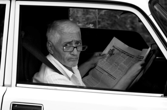 car, car seat, eyeglasses, grandfather, news, newspaper, person, television
