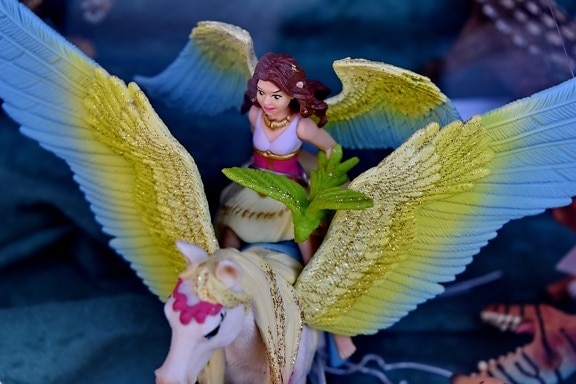 Fairy angel with colorful wings on horse toy close-up