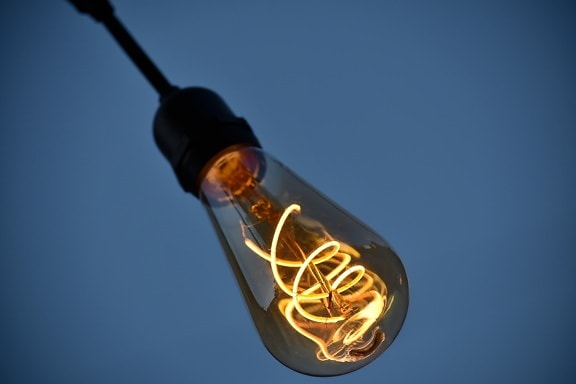 Hot illuminated wolfram (tungsten) filament wires inside old-style lightbulb