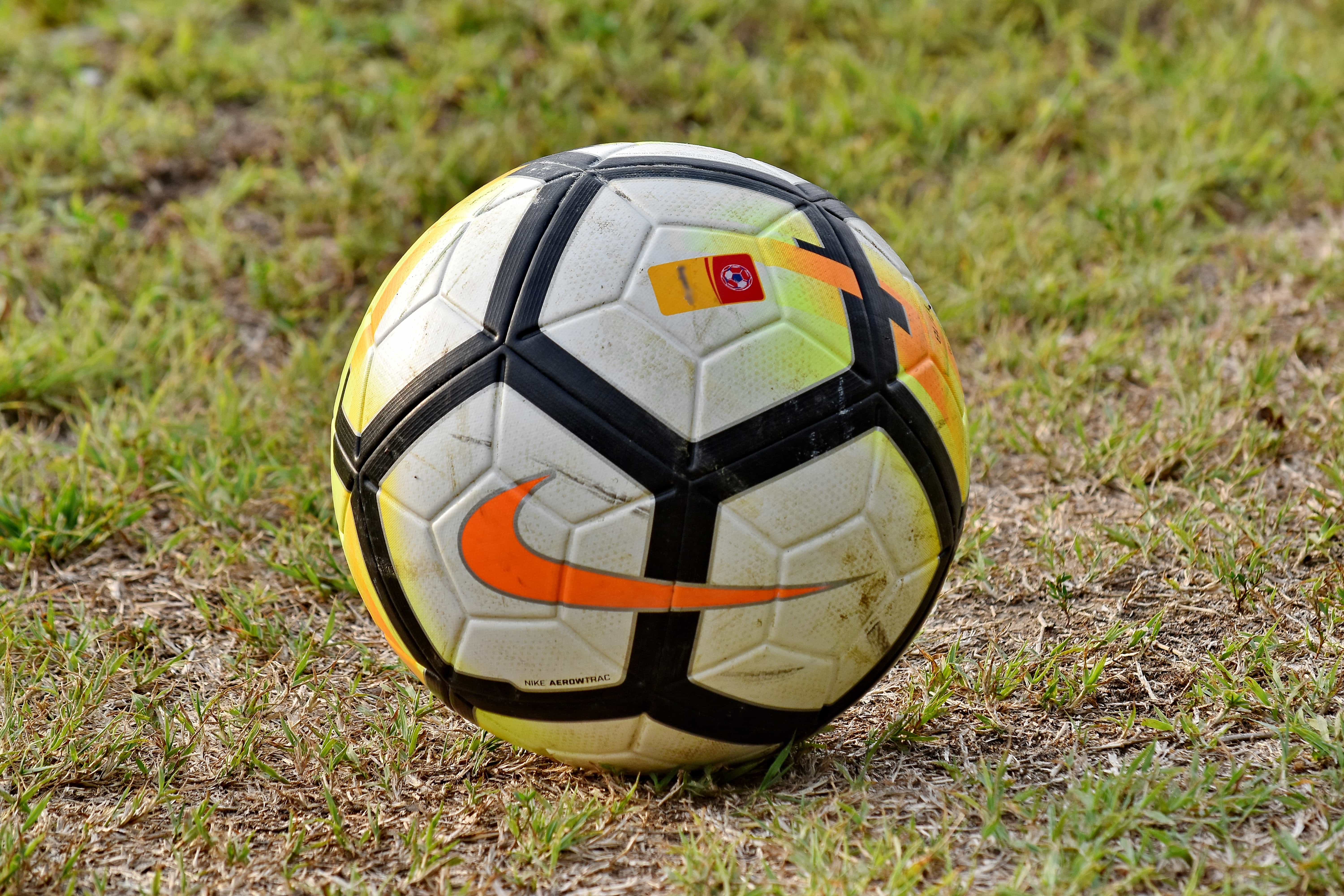 Foto Bola de futebol amarela e preta na grama verde – Imagem de