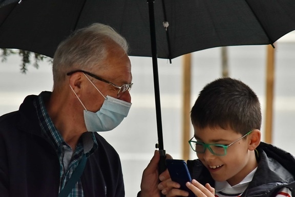 communication, COVID-19, eyeglasses, face mask, grandfather, grandson, happiness, mobile phone, smile, together