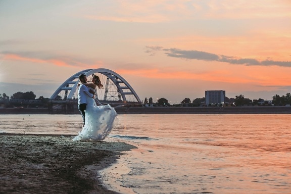 bride, groom, bridge, hugging, newlyweds, evening, sea, sunset, dawn, ocean