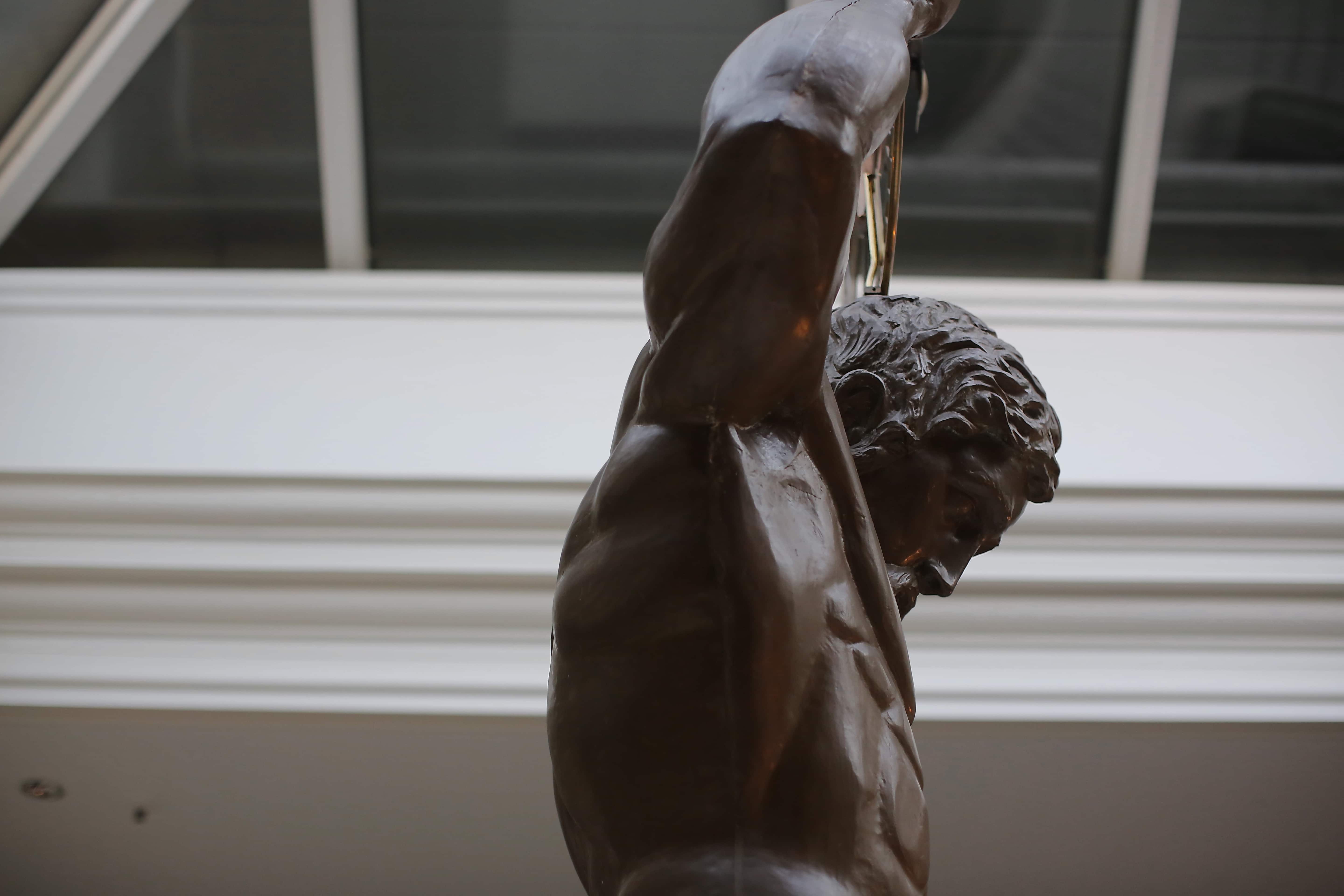 フリー写真画像 男 筋肉 彫刻 アトリウム ブロンズ アート 横から見た図 像 縦方向 屋内で
