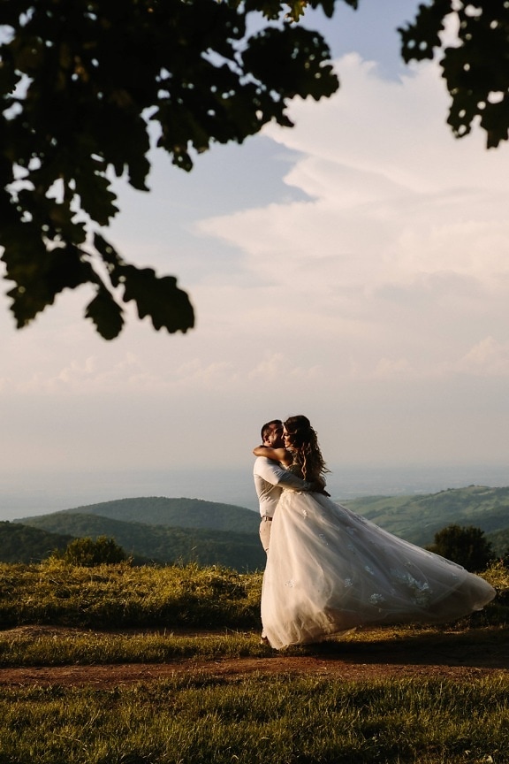 friss házasok, menyasszony, vőlegény, ölelés, dombtető, hegyoldal, lány, esküvő, naplemente, elkötelezettség