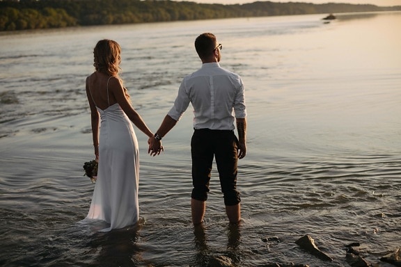 handen vasthouden, pas getrouwd, zonsondergang, oever van de rivier, water, blote voeten, benen, meisje, strand, liefde
