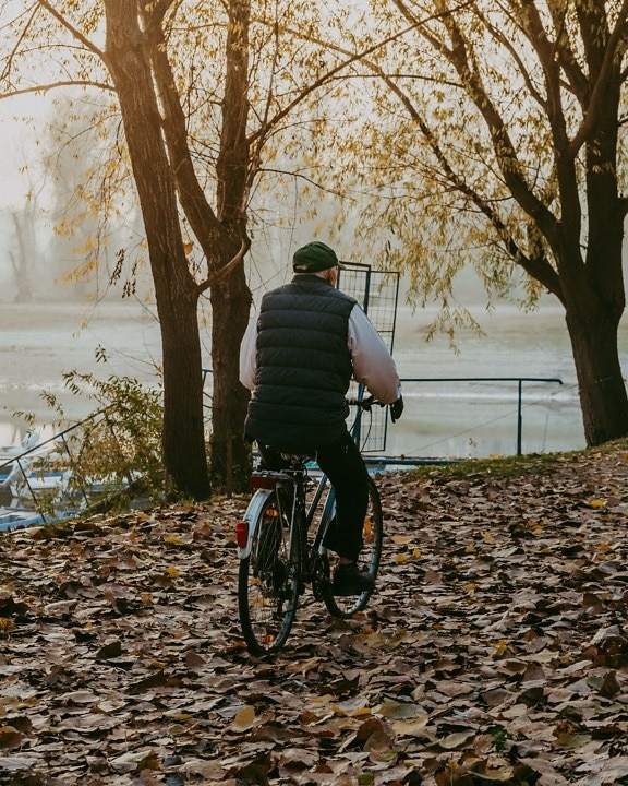 Alter Mann, Fahrrad, Herbstsaison, Flussufer, Erholung, Kälte, Wetter, Radfahrer, Radfahren, im freien