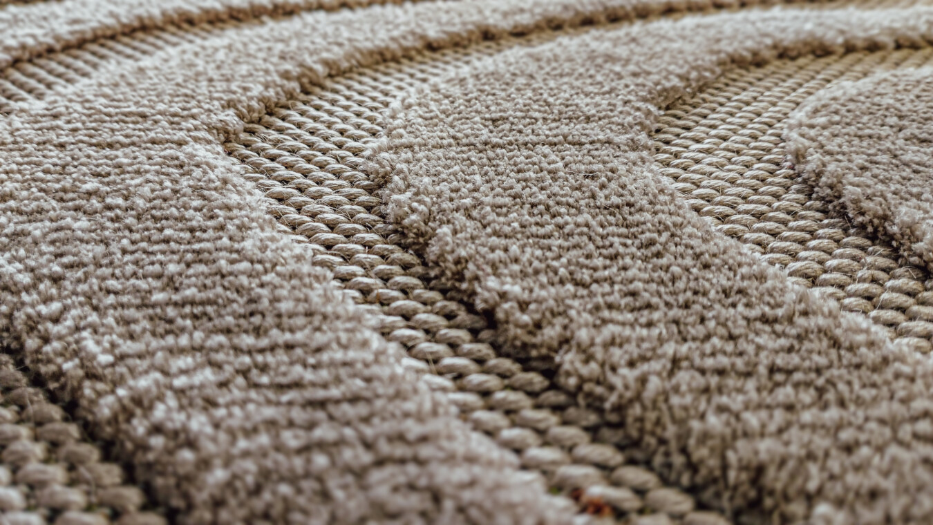 Close-up of handmade wool rug texture with details of light brown knots