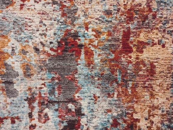 Close-up of carpet surface with colorful abstract stain texture, details of rug pattern