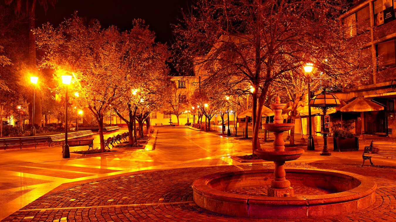 Prázdna ulica v noci s fontánou v centre mesta