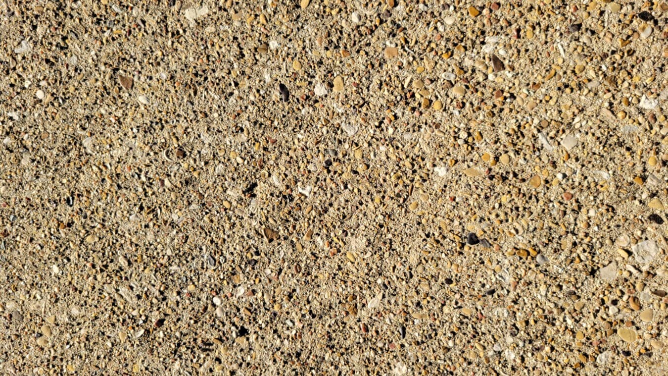 Texture de petits cailloux et de pierres sur la surface de l’asphalte en béton rugueux