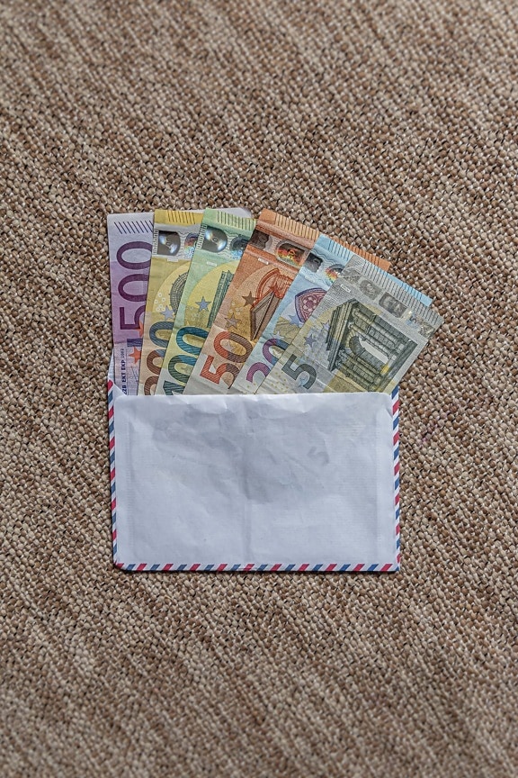 Белый конверт с денежными сбережениями в нем, иллюстрирующий деньги на покупки