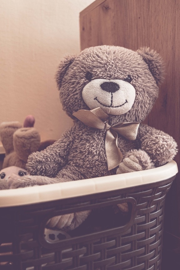 Old fashioned light brown teddy bear toy in wicker basket
