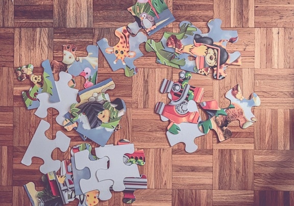 Colorful jigsaw puzzle game parts on hardwood parquet floor