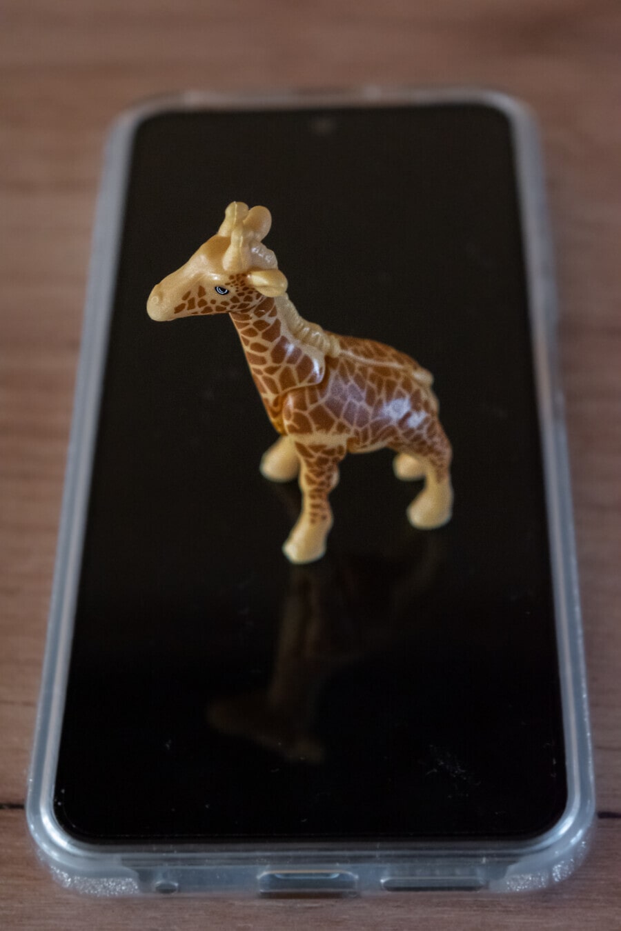 Zbliżenie miniaturowej plastikowej zabawki żyrafy na telefonie komórkowym