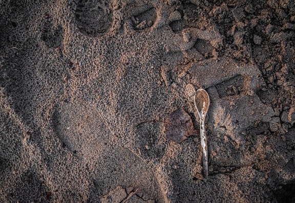 Plastic pollution of ground with spoon on wet soil