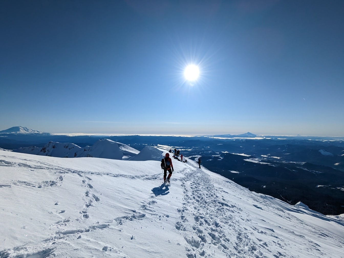 Ορειβάτες στην κορυφή του χιονισμένου βουνού o φωτεινή μέρα
