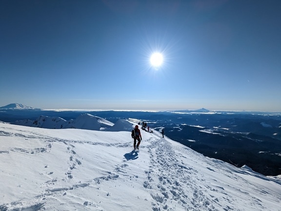 Mountain climbers on top of snowy mountain o bright day