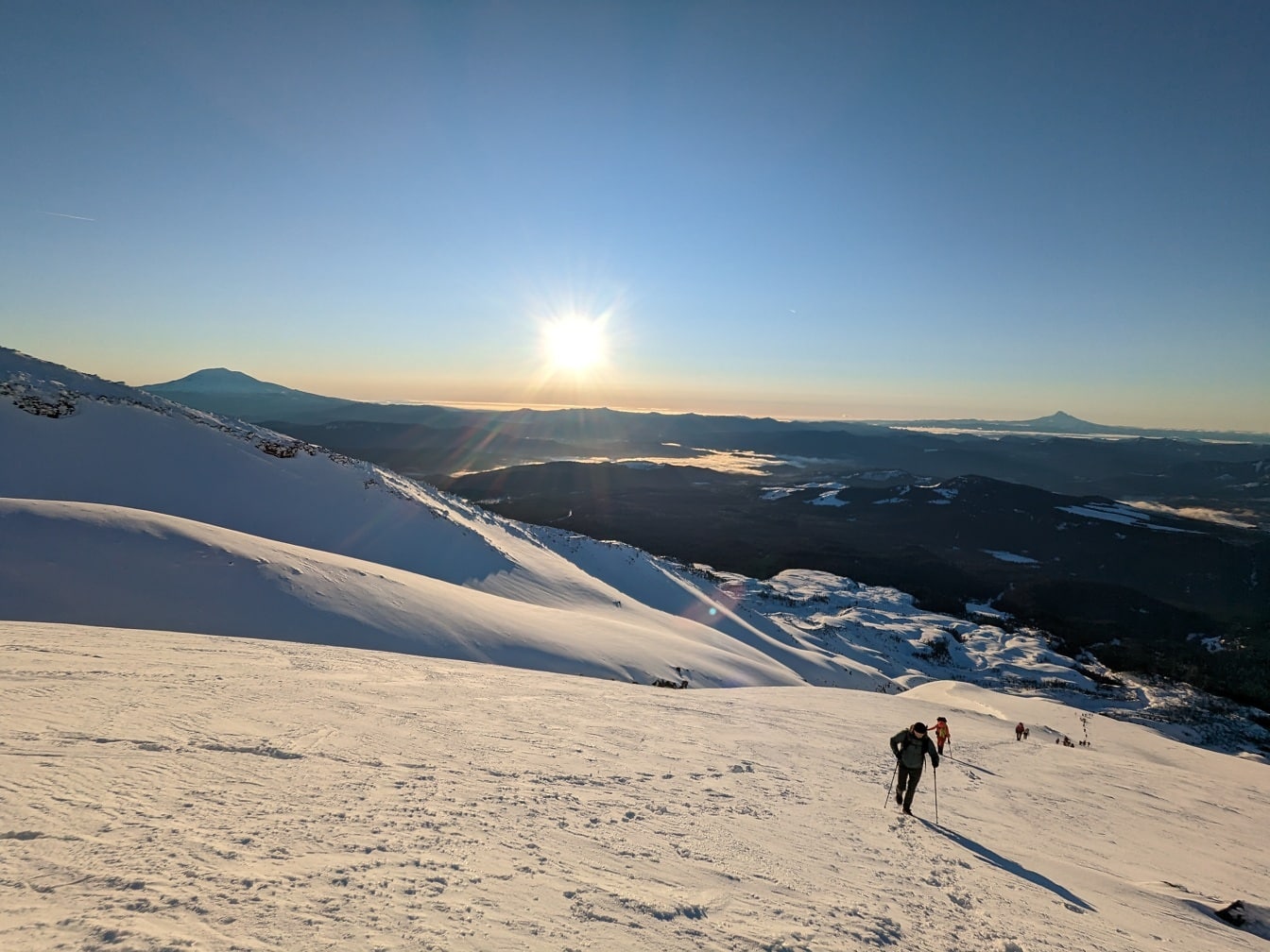 Альпинист поднимается на вершину заснеженной горы