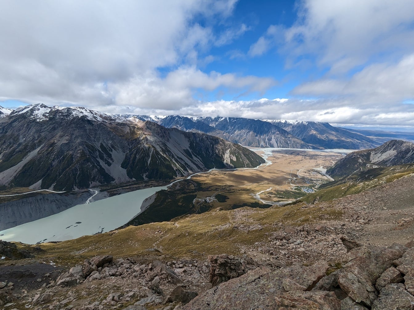 Majestátní úbočí s jezerem v údolí a ledovcovými horami v pozadí