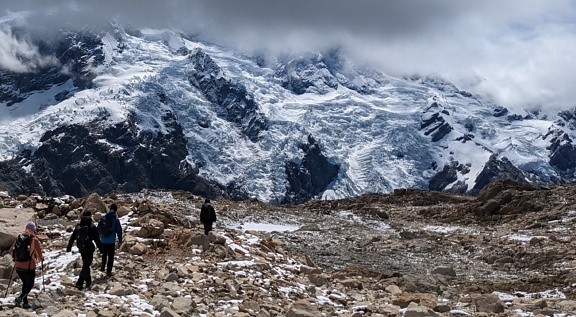 Four mountain climbers climbing to the frozen glacier