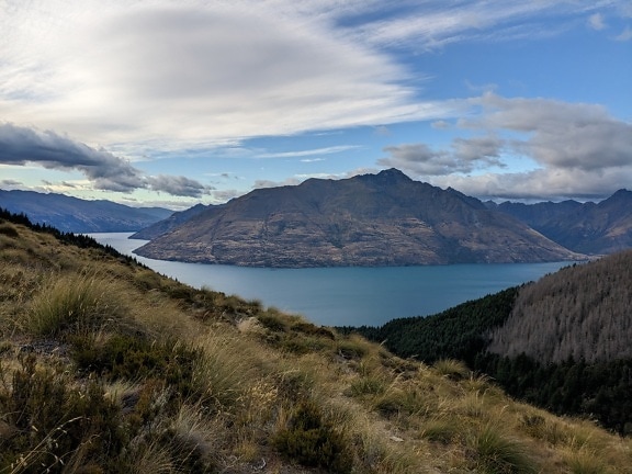 Panorama of lake and valley with mountains in background and blue sky with clouds above