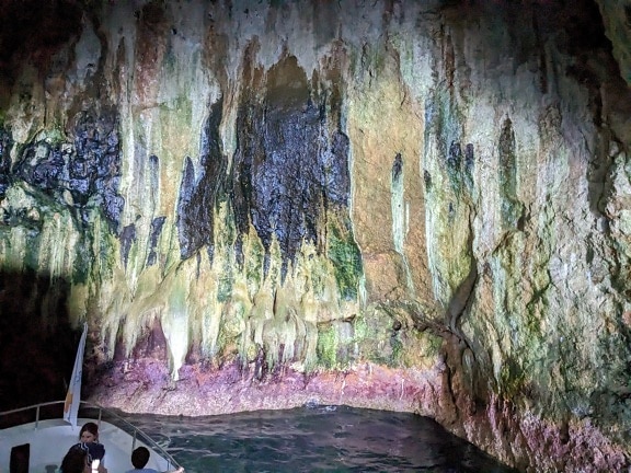Tourists on boat in colorful undergound cave