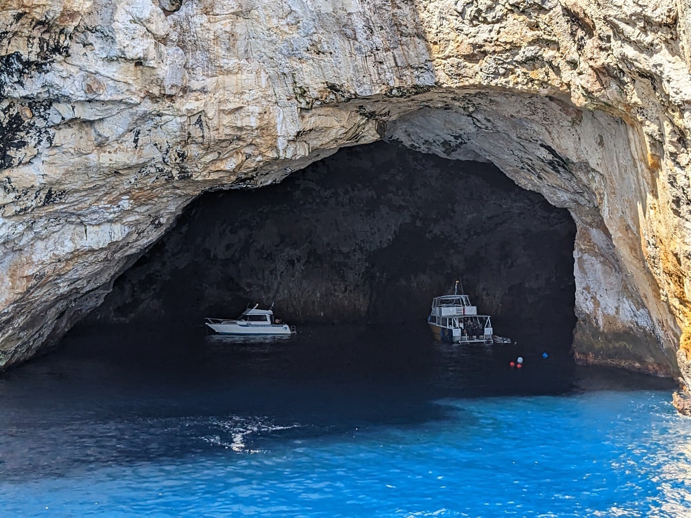 Exploration of coastline cave with small tourist yacht
