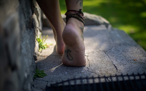 수제 가죽 발찌가 있는 문신이 있는 맨발 다리