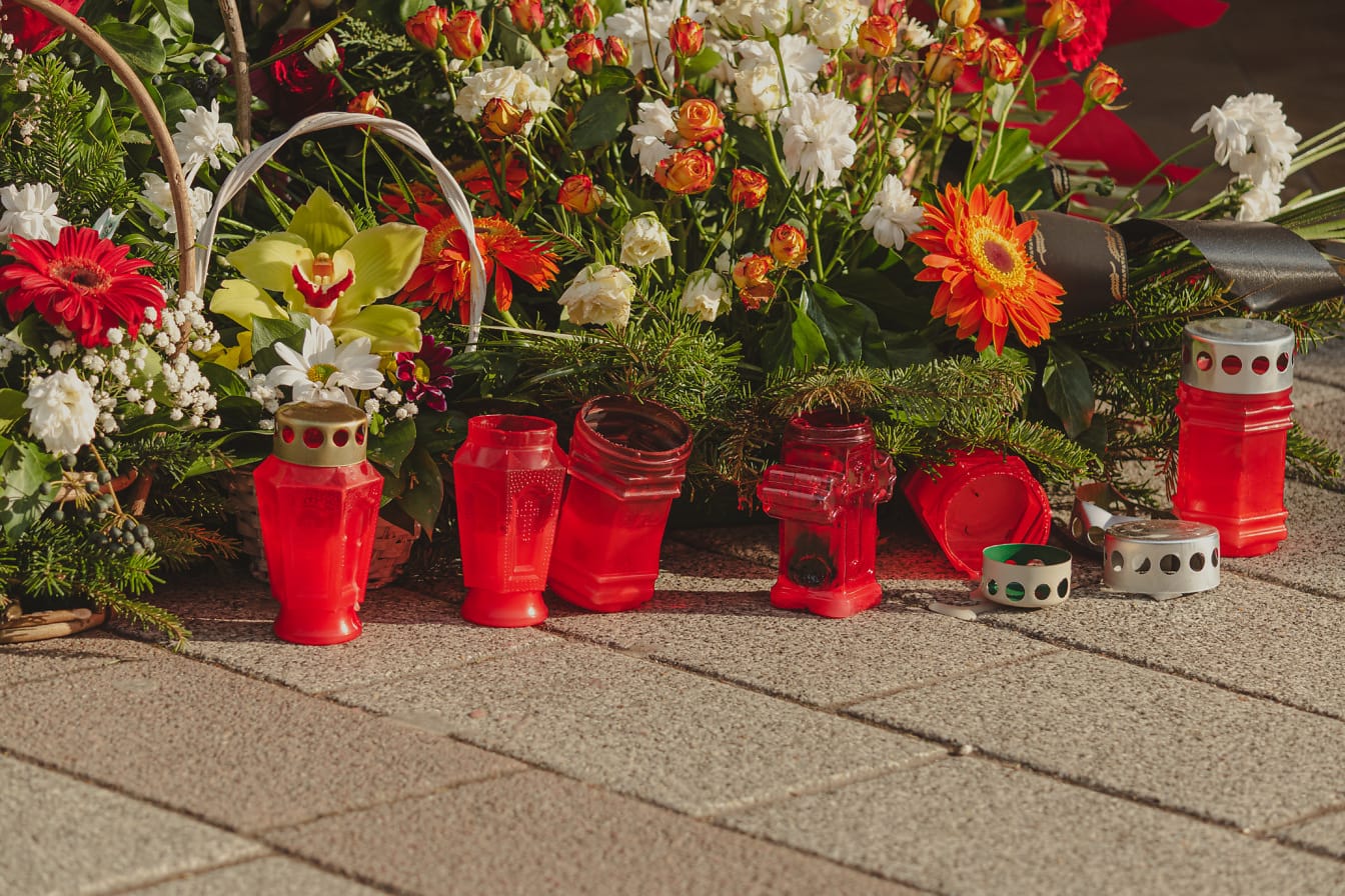 Begravningsljus med blomsterarrangemang på minnesmärke