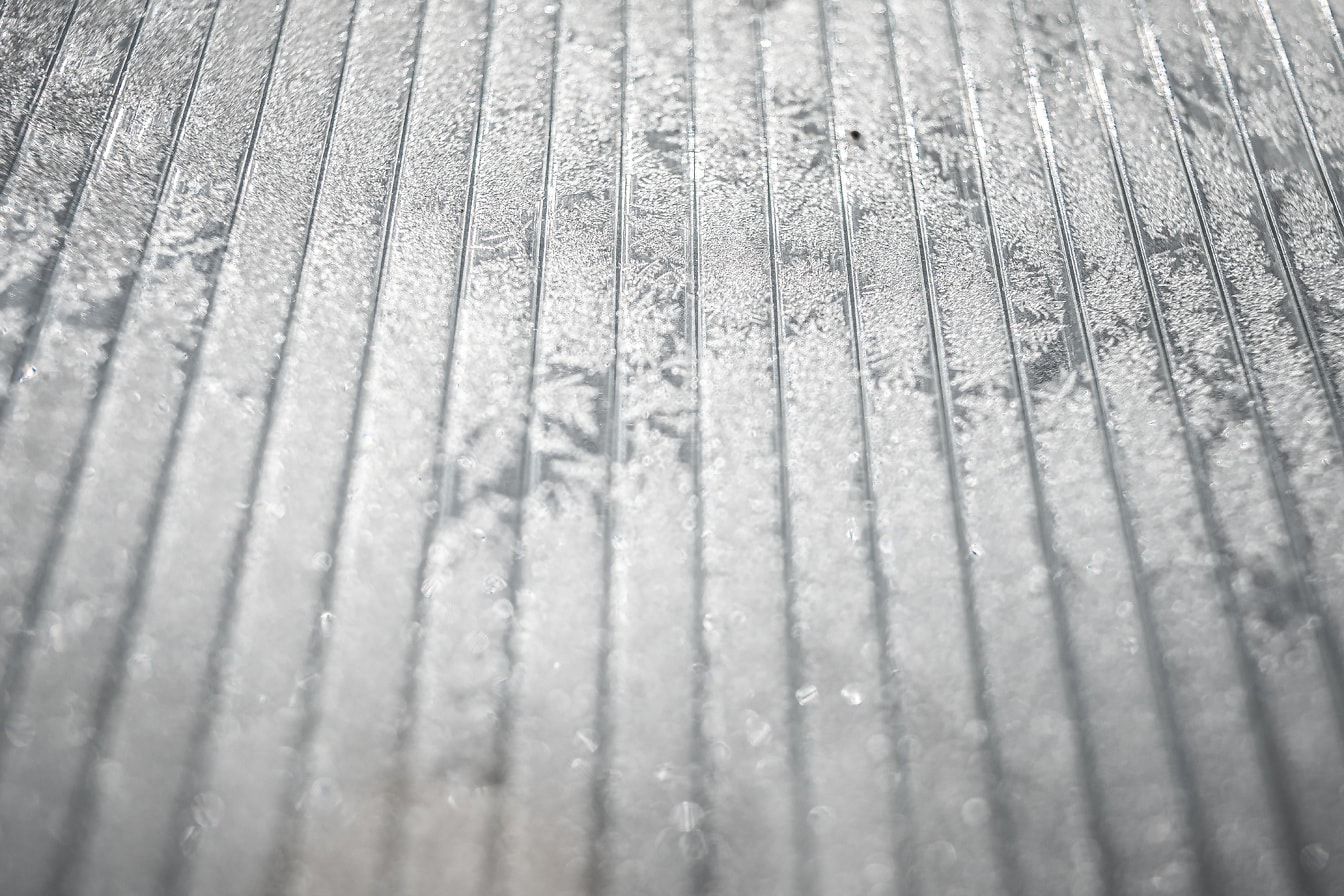 Zamarznięte szkło z teksturą płatków śniegu zbliżenie na oszronioną powierzchnię