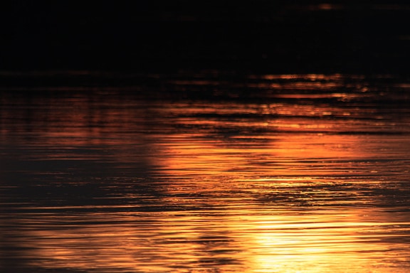 Dark orange yellow sunset over water horizon