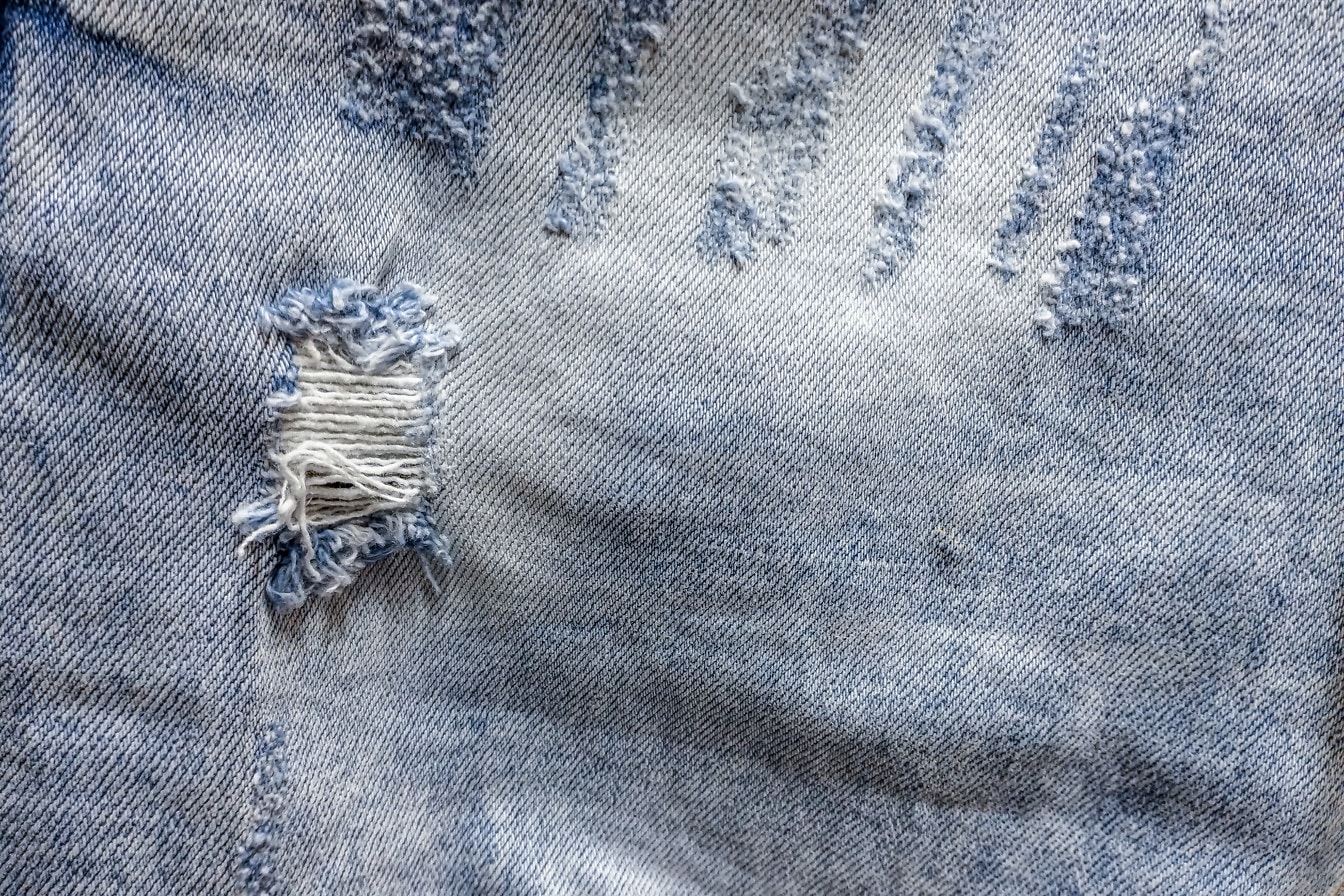 Blauw oud jeans katoenen textuur close-up gat