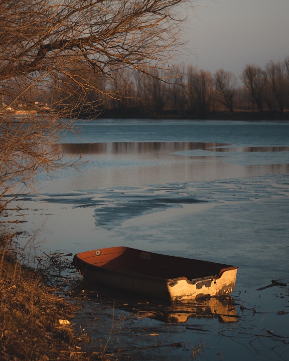 Old plastic boat on frozen lakeside
