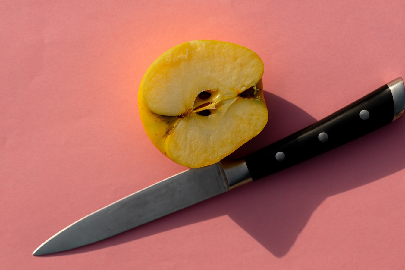 Halb geschnittener gelber Apfel mit Messer