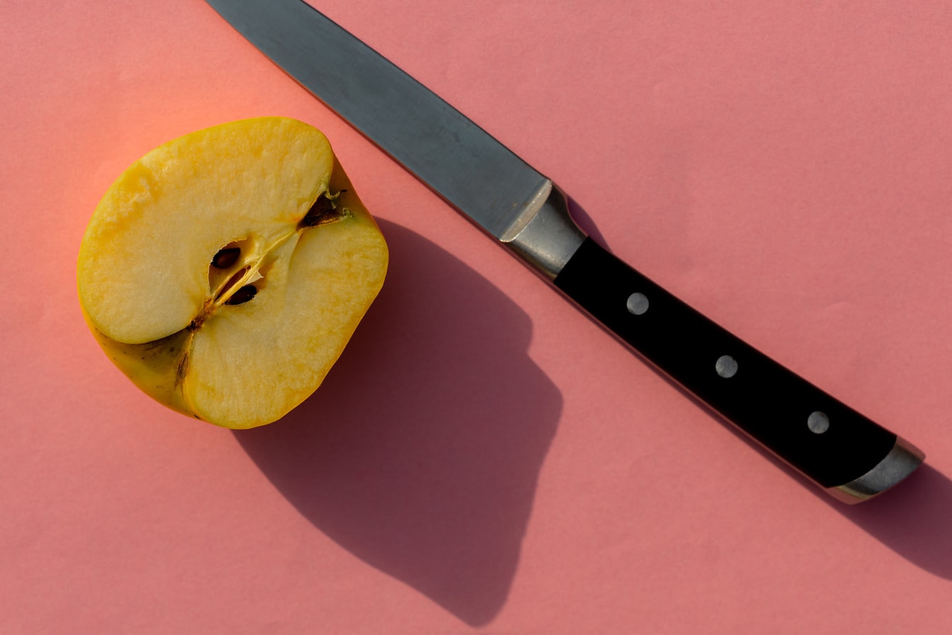 Nůž s napůl nakrájeným žlutým jablkem