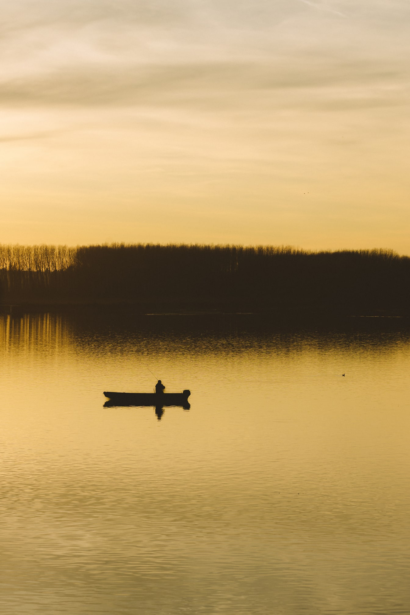 夕暮れの湖畔に浮かぶ漁船のシルエット