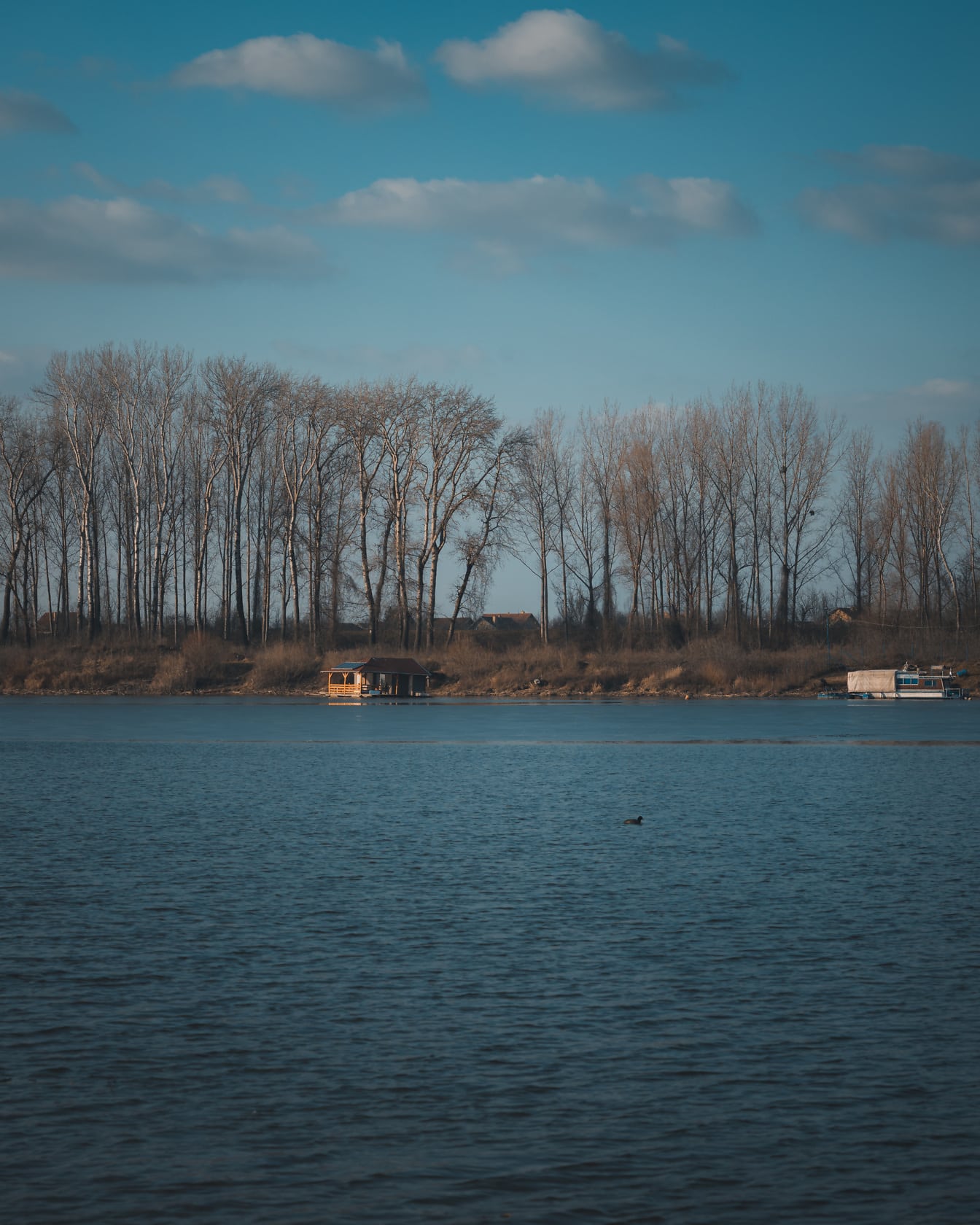 Vodný horizont jazera s lodným domčekom v diaľke