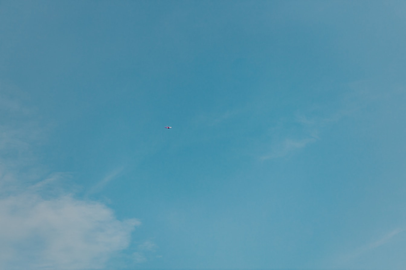 Hellblauer Himmel mit Flugzeug in der Ferne