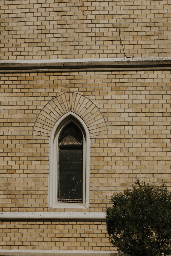 Small gothic window with arch on brick wall