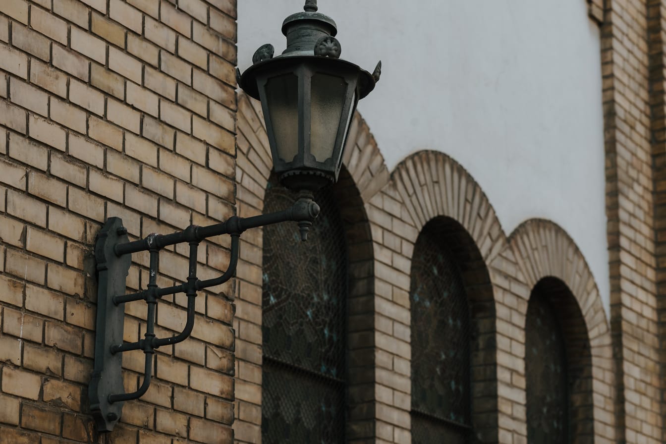 Old fashioned cast iron handmade lamp on brick wall