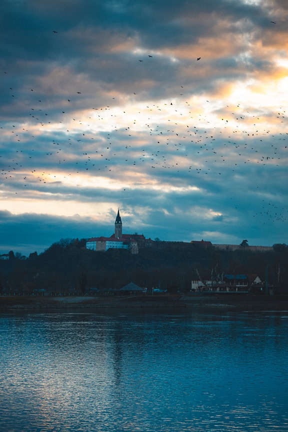 Church tower on hillside above Danube river in dusk
