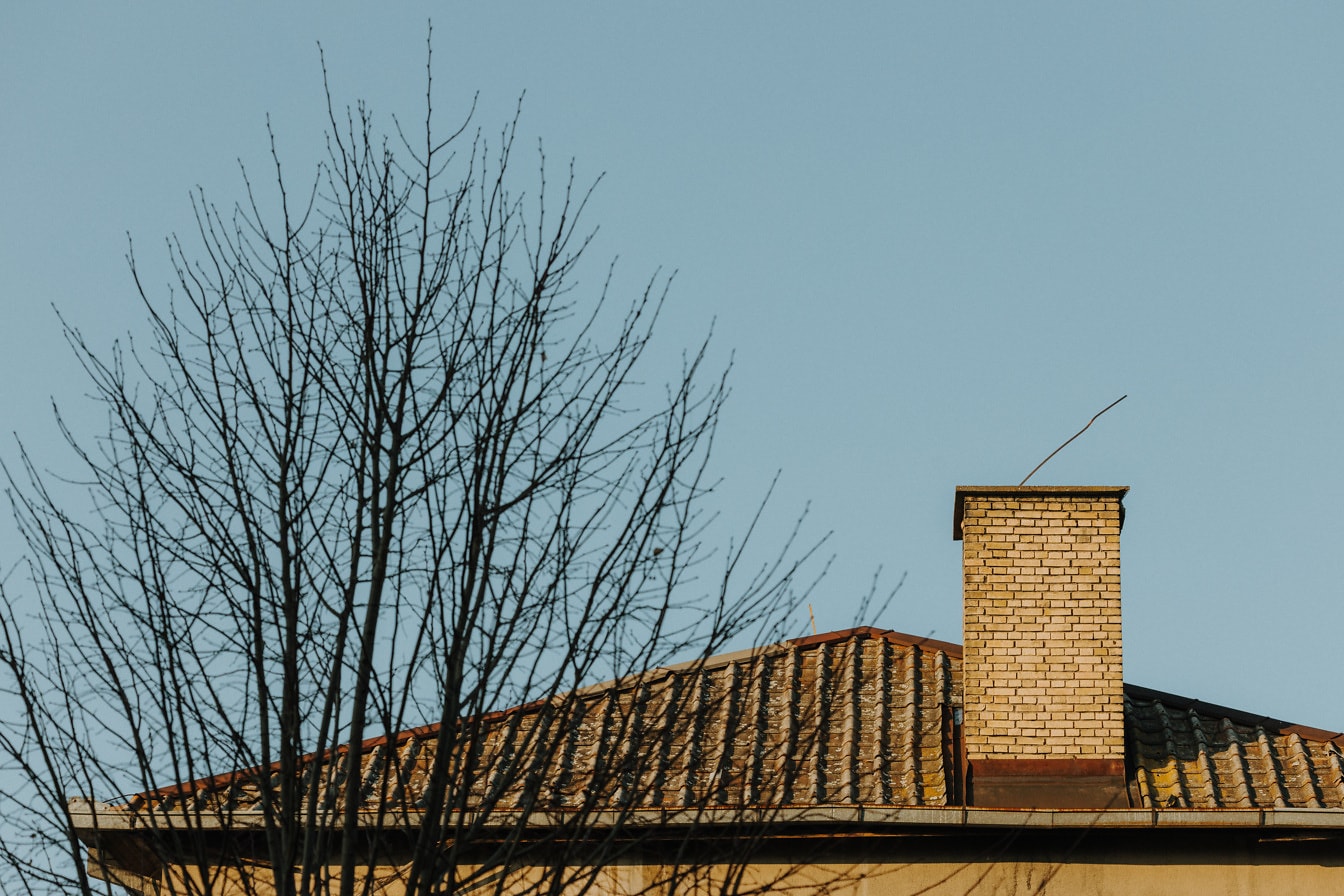 Schornstein auf Hausdach mit Dachziegeln gedeckt
