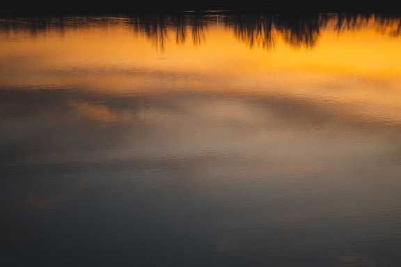 Orange yellow sunset sky reflection on calm water