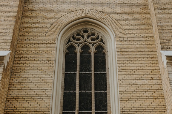 Buntglasfenster im gotischen Baustil mit Bogen an Backsteinmauer