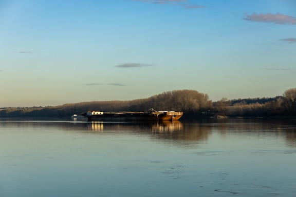 Big cargo ship with barge on calm river water