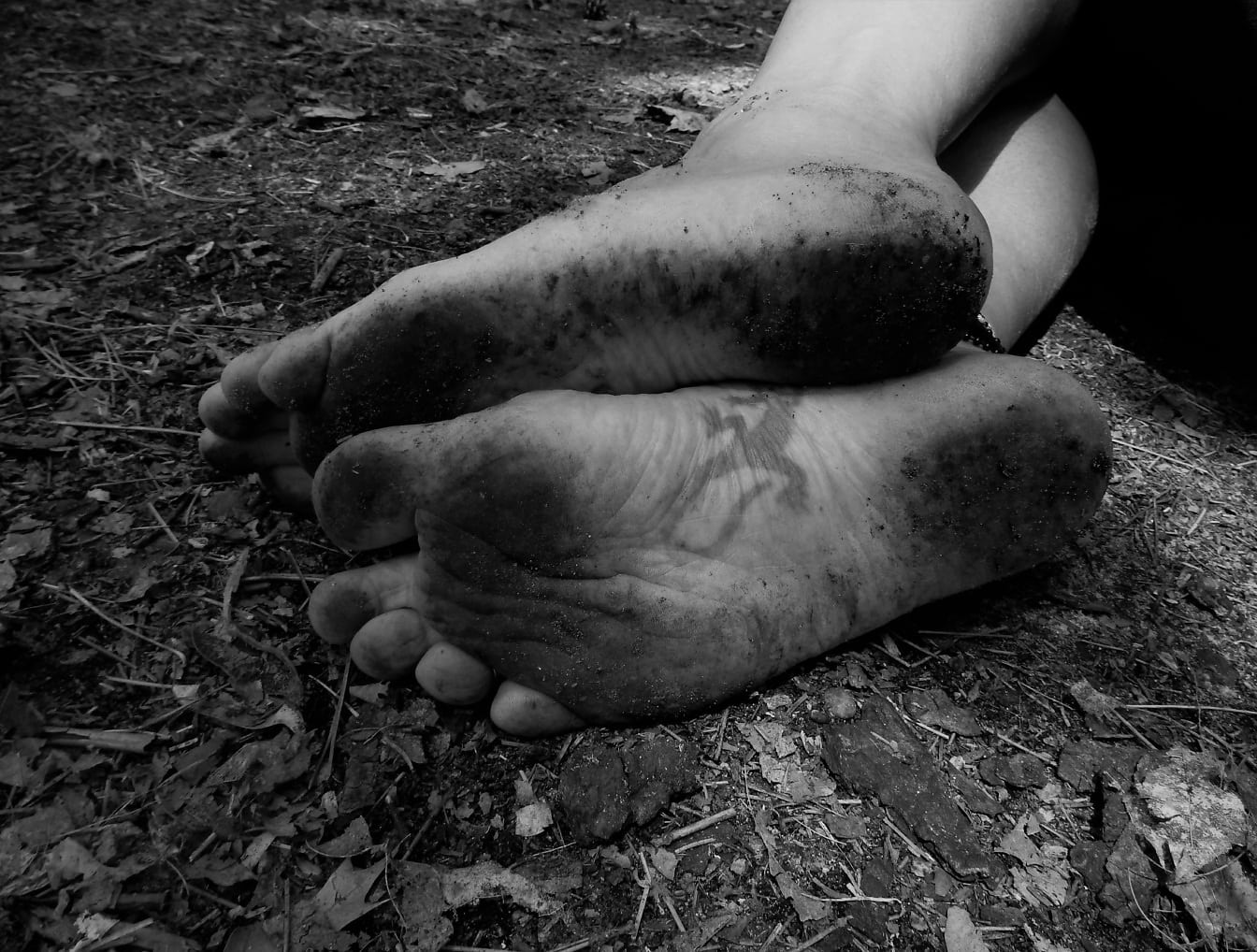 Monochrome photograph of dirty barefoot feet on ground
