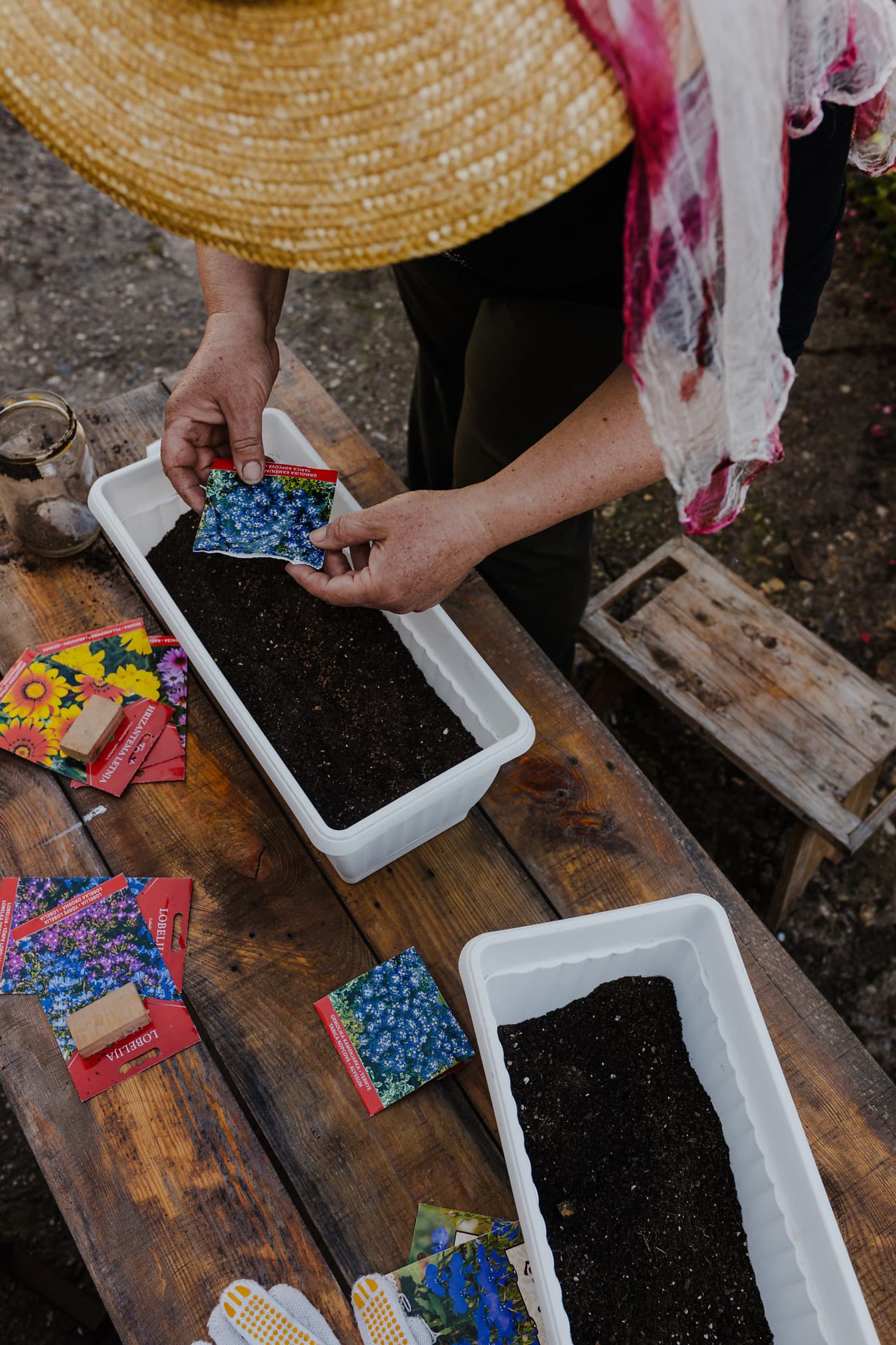 Persona anziana che fa giardinaggio piantando materiale vegetale in vaso di fiori